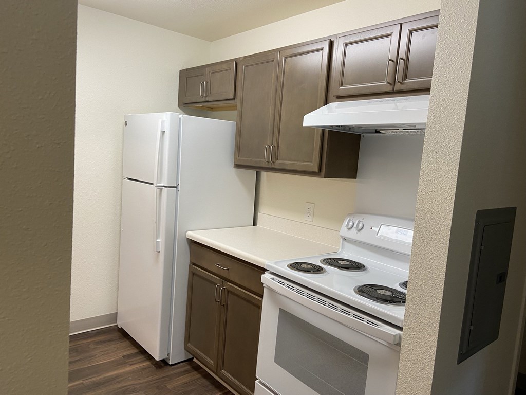 an empty kitchen with white appliances and a refrigerator